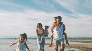 une famille qui court sur la plages avec des enfants dans les bras